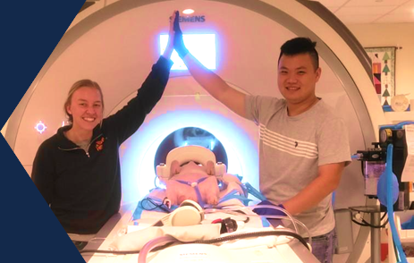 Loretta Sutkus and Zimu Li in Dr. Dilger’s laboratory high fiving in front of an MRI scanner after a four-week old piglet just completed scanning.